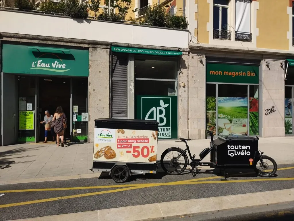 Vélo publicitaire LCDG devant un magasin L'Eau Vive